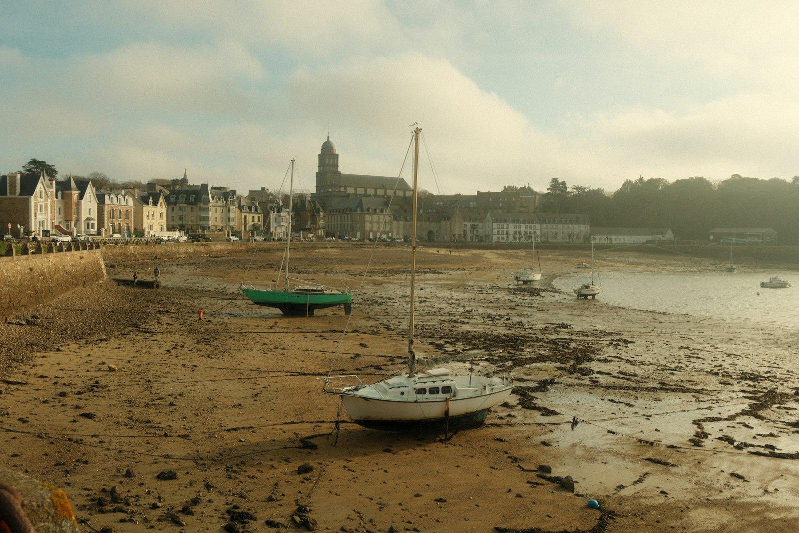 Petits voiliers posés à marée basse sur l'estran de Saint-Malo, la ville au fond