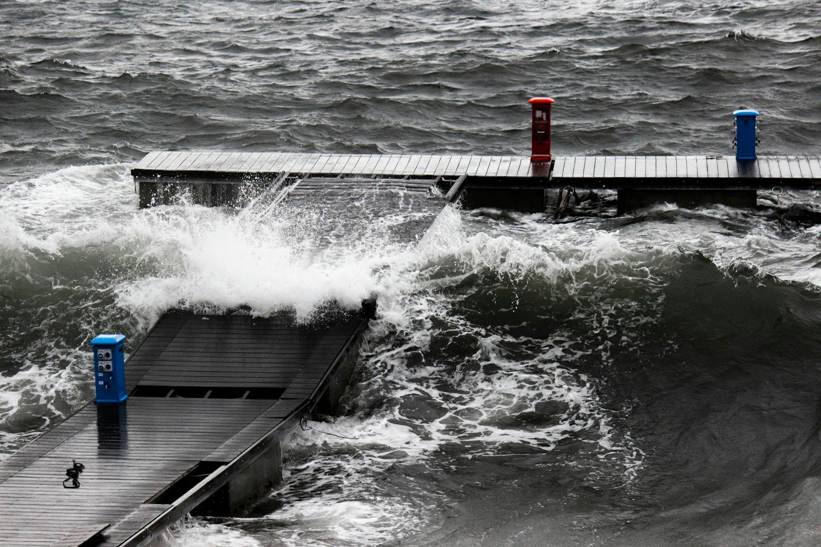 Vagues de tempête déferlant sur un ponton de port et ses bornes de service