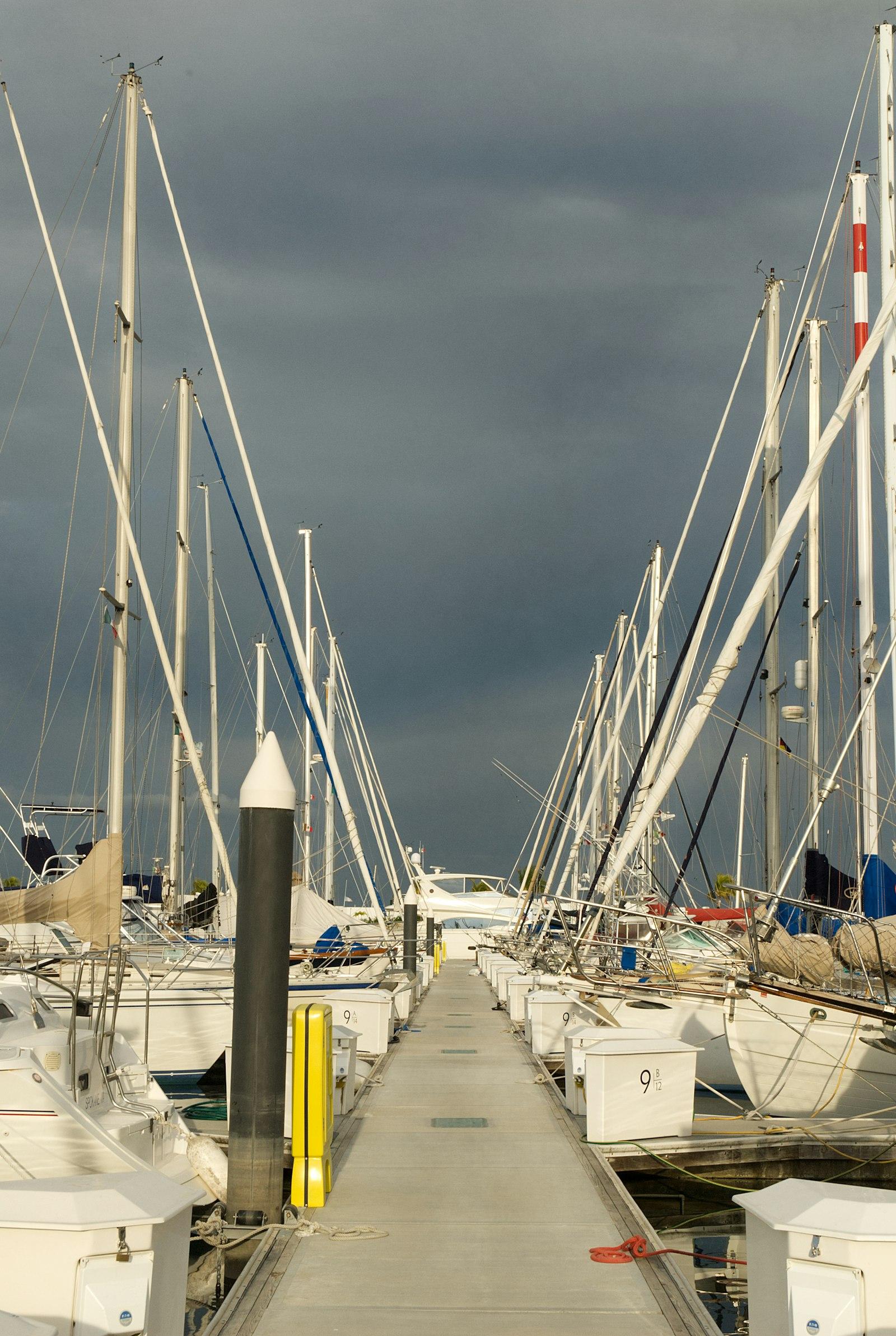 Voiliers amarrés le long d'un ponton sous un ciel d'orage